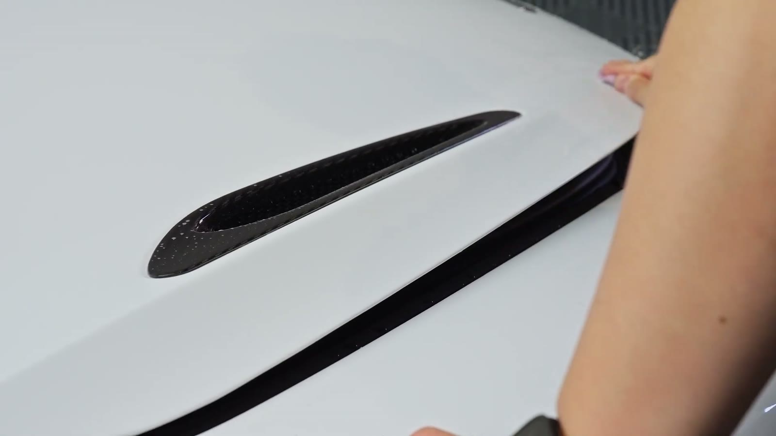 Hand pressing film flat over the McLaren bonnet vent