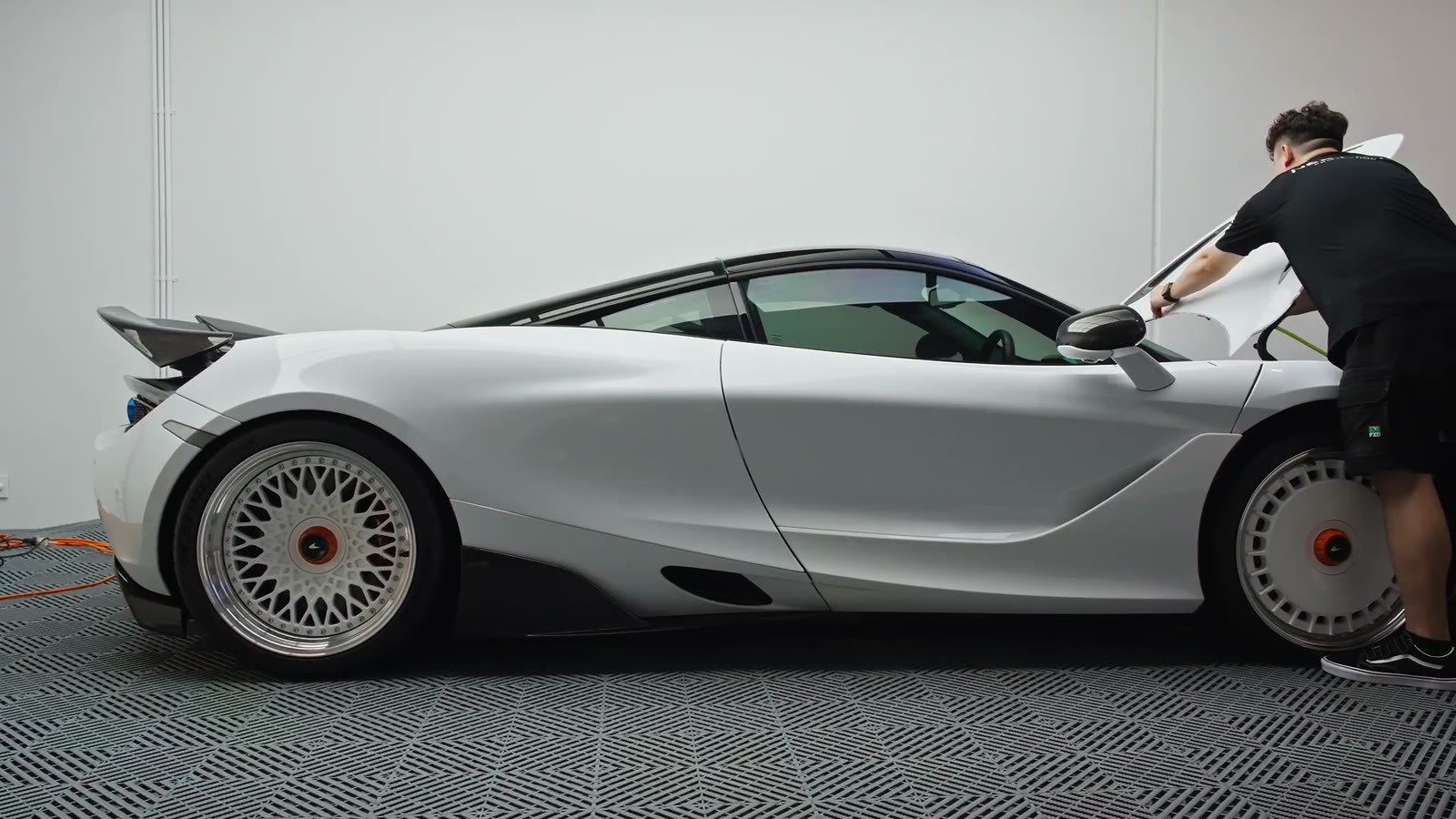 Installer laying paint protection film across the rear deck of the McLaren 720S