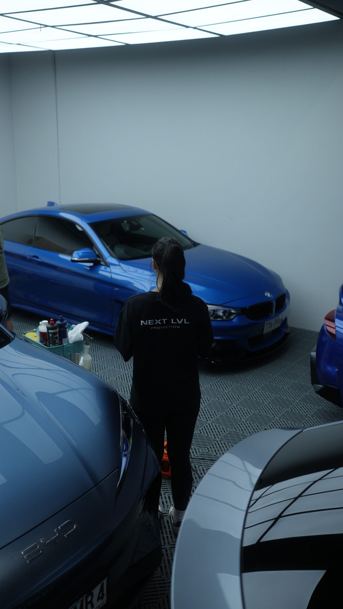 Technician inspecting a blue BMW in the studio bay