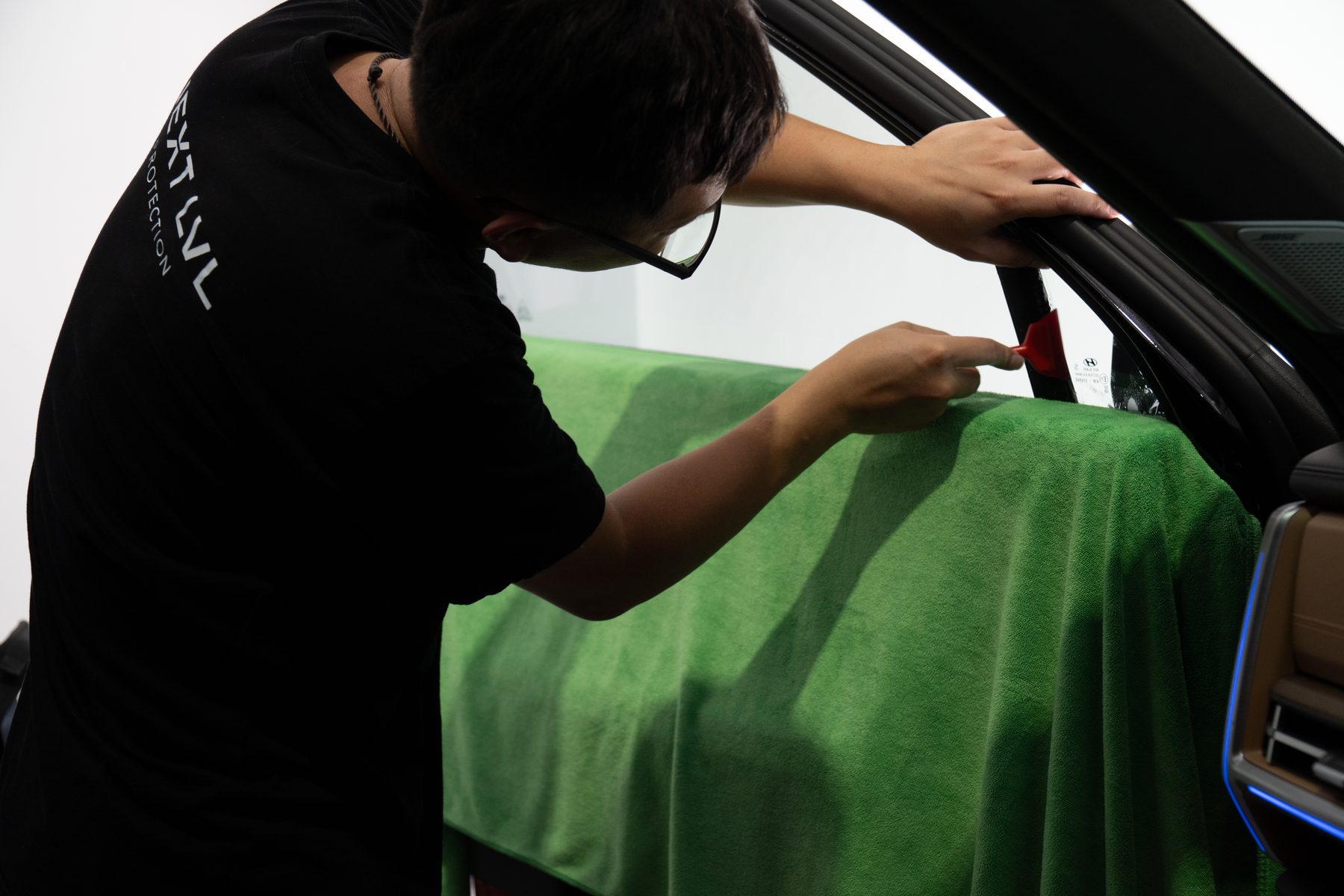 Installer fitting window film to a car door inside the Next LVL studio